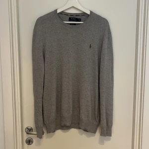 Grå bomullströja Polo Ralph Lauren - Säljer denna tröja från Polo Ralph Lauren i mjuk bomull. Slim fit-modell med rund halsringning och diskret broderad logga på bröstet. Den är 10/10 i kvalité, hör av er vid funderingar!
