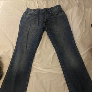 Blå jeans från Gap, straight fit - Klassiska blå jeans från Gap i rak modell med fem fickor och snygga slitningar. Jeansen har normal passform och är tillverkade i tåligt denim med kontrastsömmar. Perfekta för dig som gillar en tidlös look och vill ha ett par bekväma jeans till vardags.