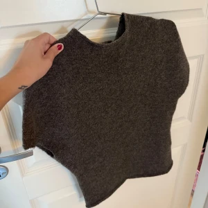 Mörkbrun stickad topp  - Mörkbrun tickad topp med korta ärmar och hög hals. Oanvänd med prislapp kvar.