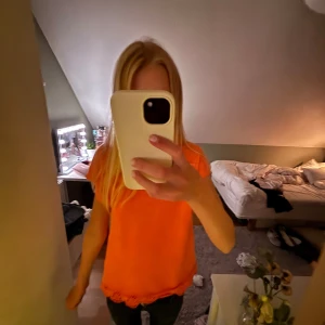 Korall topp med spets från Chloé - Superfin orange/korall topp från Chloé med korta ärmar och snygg broderad spetskant nertill. T-shirten har en enkel, rak passform och är tillverkad i mjukt bomullstyg. Köpte för 200kr second hand och tror original pris är runt 500-700kr eftersom att det är märkeströja. Storleken är för 12 år men passar mig som är 167 så den är stor i storleken.