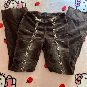 Bruna manchesterbyxor från Sisters Point - Unika bruna manchesterbyxor från Sisters Point med snygga vita snörningsdetaljer längs framsidan. Byxorna har råa kanter nertill och är i ett mjukt manchestermaterial.                                                                   Midjemått = 37 cm men går att justera lite.                  Längd = 103 cm
