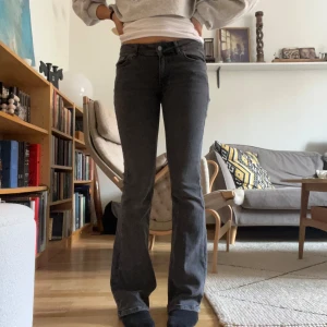 Grå bootcut jeans från Junkyard - Snygga grå jeans från Junkyard med bootcut-modell och klassisk femficksdesign. Jeansen har en mörkgrå tvätt, raka ben som blir vidare nedtill och coola bakfickor med broderad detalj. Perfekta för en avslappnad men trendig look.