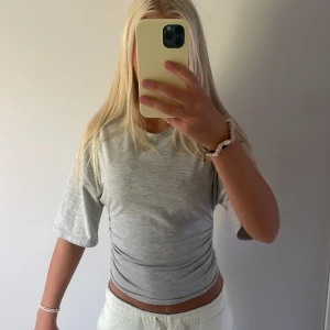 Ljusgrå croppad t-shirt med snörning - Snygg ljusgrå t-shirt med croppad passform🩷 köpt från Gina i storlek xs men funkar som storlek S också ❤️Använd några gånger och säljer för att jag inte använder längre🥰