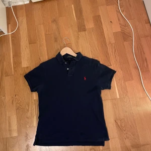 Mörkblå piké från Polo Ralph Lauren - Mörkblå pikétröja från Polo Ralph Lauren i slim fit-modell. Den funkar i s också