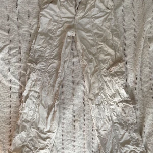 Beiga cargopants från BDG Urban Outfitters - Säljer ett par beiga cargopants från BDG Urban Outfitters i storlek S. Byxorna har flera fickor, elastisk midja och är tillverkade i ett lätt bomullsmaterial. Perfekta för en avslappnad och trendig look.