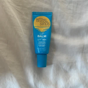Bondi Sands Lip Balm SPF 50+ - Läppbalsam från Bondi Sands med SPF 50+ och smak av toasted coconut. Kommer i en blå tub på 10g, perfekt att ha med sig i väskan för att skydda läpparna mot solen. Ger både fukt och solskydd med en tropisk känsla.