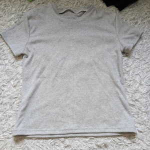 Grå basic t-shirt i bomull - Enkel och stilren grå t-shirt med rund hals och korta ärmar. Perfekt för en clean och avslappnad look. Mjuk och skön i bomull, passar till allt och är lätt att matcha med andra plagg. (Sitter inte tajt)