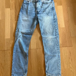 Jack and Jones ljusblå jeans - Jack and Jones jeans i ljusblå tvätt. Rak passform med normal midja och fem fickor. Jeansen har den ikoniska knäppningen framtill och är tillverkade i slitstarkt bomullsjeans. Perfekta för en avslappnad och tidlös stil. 28/32