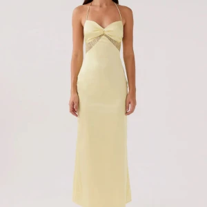 Ljusgul Peppermayo långklänning med spetsdetaljer - Snygg långklänning i ljusgul satin med smala axelband och öppen rygg. Klänningen har en twistad detalj vid bysten och spetsinfällningar under bysten för en extra touch. Perfekt för dig som vill sticka ut med en elegant och feminin look. Inga defekter 