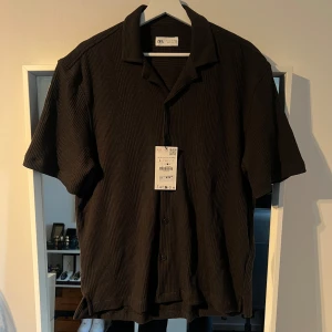 Grå/grön skjorta från Zara - Svart skjorta från Zara i storlek L med ribbad struktur. Aldrig andvänd med tagen fortfarande kvar!