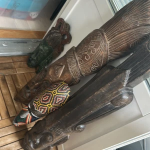 Afrika stati  - Bilderna visar flera snidade träskulpturer och masker med färgglada och detaljerade mönster. Det finns ingen bok synlig på bilderna, endast konstföremål. Ingen information om titel, författare eller bokinnehåll kan utläsas.