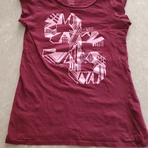 T-shirt - Lila t-shirt från WA Action Sports med coolt grafiskt tryck i ljusrosa framtill. Klassisk rund hals och korta ärmar. Den har ett litet hål. Tillverkad i mjuk bomull, perfekt för en avslappnad stil.