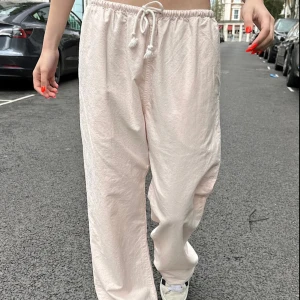 Brandy Melville Ljusrosa linen byxor med snörning - Säljer ett par ljusrosa linen byxor med relaxed passform och snörning i midjan. Byxorna är vida och tillverkade i ett mjukt material som känns skönt mot huden. Perfekta för chill dagar eller när du vill ha en avslappnad stil.