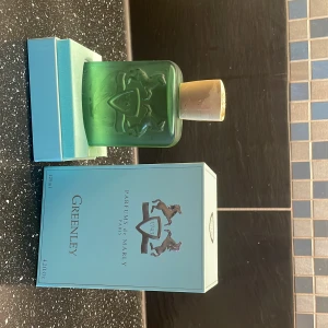 Parfums de Marly Greenley 125ml - Greenley från Parfums de Marly är en lyxig parfym i en grön frostad glasflaska med snyggt ingraverad logga och guldfärgat lock. Flaskan rymmer 125 ml och kommer i en stilren ljusblå kartong med bronsfärgade detaljer. Perfekt för dig som gillar exklusiva dofter. Som ni ser har den en skråma i boxen och kvitto finns!