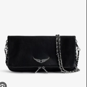 Svart Zadig & Voltaire axelväska i skinn - Säljer en Zandig & Voltaire väska i nytt skick. Säljer pga den inte kommer till användning.  Cool svart axelväska från Zadig & Voltaire i skinn med silverfärgad kedjerem och ikonisk vingedetalj framtill. PRIS KAN DISKUTERAS VID SNABB AFFÄR 