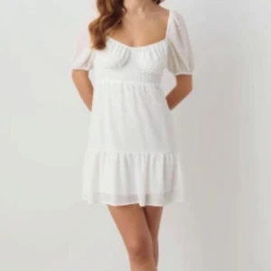 Vit klänning med puffärm och snörning - Kort klänning från gina tricot med puffärmar, volangkant och snörning i ryggen. Använt endast en gång på studenten 🤍