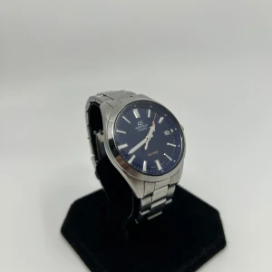 Casio Edifice klocka - Stilren Casio Edifice klocka med blå urtavla och datumvisning. Boett och länk i silverfärgat metall, klassisk rund form och tydliga indexmarkeringar. Perfekt accessoar för dig som gillar en clean och modern look.