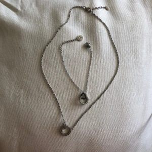 Fint halsband och armband i äkta silver - Set med halsband och armband i äkta silver. Båda har runda berlocker med gnistrande stenar/diamanter runt hela cirkeln för en stilren och glittrig look. jätte fina men har inte kommit till användning typ nån gång (fick dom i present för många år sen).
