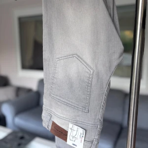 Grå skinny jeans  - Snygga grå skinny jeans från Lindex Denim design. Jeansen har klassisk femficksmodell, bälteshällor och knappgylf. Den har en ljusgrå tvätt som ger en fräsch look.