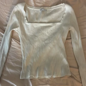 Vit ribbad långärmad tröja Zara - Säljer en vit ribbad långärmad tröja från Zara med fyrkantig urringning. Tröjan är i stretchigt material och har en slim passform som sitter snyggt på kroppen. Perfekt att styla med jeans eller kjol för en clean look.