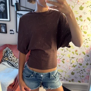 Brun topp från Nelly - Snygg brun croppad topp från Nelly med rund halsringning och vida korta ärmar. T-shirten har en clean look och är tillverkad i mjuk bomull, perfekt till jeans eller kjol. Enkel och trendig modell som är lätt att styla. Prislapp kvar🤎🤎🤎