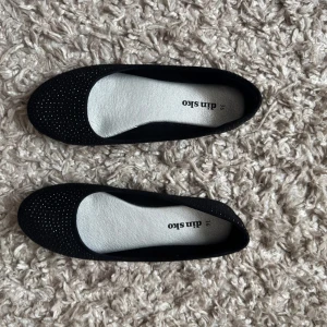 Svarta glittriga ballerinaskor 36 - Snygga svarta ballerinaskor från din sko med glittriga detaljer på ovansidan. Storlek 36, jättefina för att liva upp en outfit💞Skorna har en rund tå och en bekväm sula.