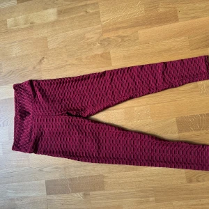 Vinröda scrunch tights  - Säljer ett par vinröda tränings tights med scrunch-detalj bak och coolt bikakemönster. De är tighta och har hög midja, perfekta för gymmet eller chill hemma. Materialet är stretchigt och mjukt, vilket gör dem riktigt bekväma att ha på sig.