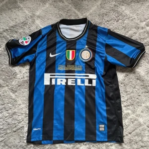 Inter Milan 2010 Finaltröja Nike - Inter Milan fotbollströja från Champions League-finalen 2010. Klassisk blå och svart randig design med klubbmärke, Nike-logga, Broderad finaltext på bröstet och italienskt mästerskapsmärke. Storlek M och ny!