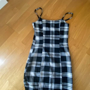 Rutig klänning från H&M - Supersnygg kort klänning med svartvitt rutigt mönster från H&M. Tight passform med smala axelband. 