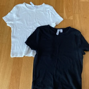 2-pack ribbade t-shirts från H&M Divided - Två ribbade t-shirts från H&M Divided i storlek S. En svart och en vit, båda med rund hals och korta ärmar. Perfekta basplagg i mjuk bomull som funkar till allt. Snygg passform och enkel stil som alltid är rätt.