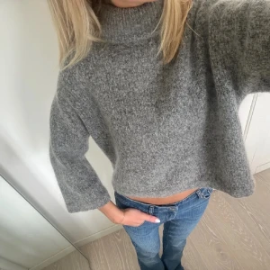 Grå stickad polotröja  - Supermysig grå stickad polotröja och vida ärmar. Perfekt för lager-på-lager och chill höst- och vinterstil. Tjockt, fluffigt material som känns lyxigt och värmande. Enkel att matcha med jeans eller kjol.