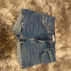 Blå jeansshorts - Snygga blå jeansshorts från Gina som jag klippt själv.  Klassisk modell med råa, fransiga kanter och femficksdesign. Shortsen har normal passform och är perfekta för varma dagar. De är normala i storlek och är mid/low rise.