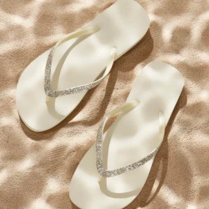 Glittriga beige sandaler strl 39 - Snygga beige sandaler med glittriga remmar i silver. Perfekta för stranden eller varma dagar. Platt sula och klassisk flipflop-modell i syntetmaterial. Lätta att matcha med somriga outfits och ger en fräsch vibe.