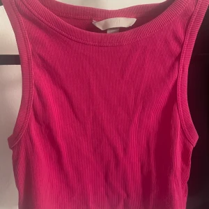 Ribbad rosa linnetopp från H&M - Säljer en ribbad rosa linnetopp från H&M. Toppen är ärmlös med rund halsringning och har en tight passform. Perfekt att styla med jeans eller kjol för en fräsch look.
