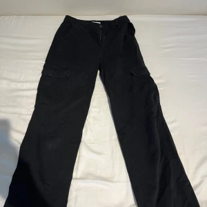 Svarta cargopants med raka ben - Svarta cargopants med raka ben.  Byxorna är från Pull&Bear och har en normal passform. Byxorna är lagade längst ner (syns på sista bilden) men det är inget som märks när man har på sig dem💕