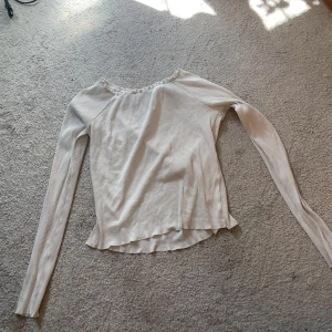 Vit ribbad långärmad topp från Lindex - Säljer en vit långärmad topp från Lindex med smala ribbade ränder och söt volangkant vid halsringningen och ärmslut. Modellen är figurnära och stretchig, perfekt till jeans eller kjol. Enkel och stilren, passar till många olika looks. Liten skada vid ena ärmen.