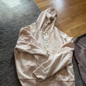 Beige hoodie från H&M Sport - Mysig beige hoodie från H&M Sport med huva och breda snören. Tröjan har en relaxed passform och är tillverkad i mjuk bomullsblandning. Perfekt för chill dagar eller när du vill vara bekväm. Långärmad och enkel att matcha med jeans eller leggings.