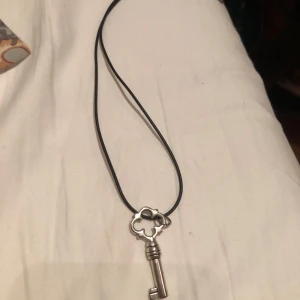 Halsband med nyckelberlock i silverfärg - Coolt halsband med svart snöre och en vintage nyckel i silverfärg som hänge. Perfekt accessoar för dig som gillar unika detaljer! Helt perfekt skick :)🩷