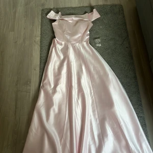 Ljusrosa axelbandslös långklänning - En helt ny superfin ljusrosa långklänning i glansigt satinliknande material från bubbleroom (etikett saknas!) Ursprungligen 5999 kr. Klänningen är axelbandslös med bred volang upptill och har en elegant, utsvängd kjol. Dold dragkedja bak och fickor i sidorna. Perfekt för bal eller övrig fest🌸//Pris kan diskuteras!