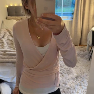 ljusrosa omlottopp - Supersöt ljusrosa omlottopp i så skönt och luftigt material!! Endast använd två gånger, fläcken på armen är ifrån butiken, men går nog bort i tvätten då jag tvättar kläderna innan jag skickar iväg dem, annars säger jag till såklart💗köpt för 150kr, pris går alltid att diskutera