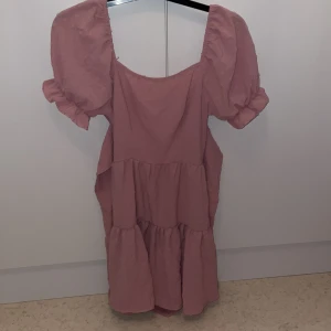 Rosa volangklänning från SHEIN - Supersöt rosa klänning från SHEIN med puffärmar, volanger och öppen rygg med två stora rosetter där man kan knyta hur man vill. Klänningen har en luftig passform och är perfekt för varma dagar. 💗