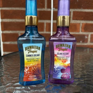 Hawaiian Tropic Body Mist duo - Två tropiska body mists från Hawaiian Tropic: Summer Dreams med doft av passionsblomma, mango och mysk i blå flaska, samt Island Resort med orkidé och granatäpple i lila flaska. Båda flaskorna rymmer 100 ml och har guldiga spraykorkar. Perfekt för dig som älskar fräscha, exotiska dofter. Se bild 4 för kvarstående mängd :)
