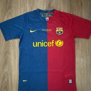 FC Barcelona Messi 10 Final Roma 2009 tröja - FC Barcelona matchtröja från Champions League-finalen 2009 med Messi 10 på ryggen. Klassisk halvblå, halvröd design med gula detaljer, klubbmärke och Nike-logga. Tillverkad i lätt, ventilerande NikeFIT-material. Perfekt för dig som älskar fotboll och Barca.                                 Barcelona 2008/2009 Home Kit, Storlek Herr S och aldrig använd.