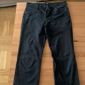 Mörkblåa raka byxor från LC Waikiki - Mörkblåa byxor från LC Waikiki med raka ben och klassisk femficksdesign. Byxorna har dragkedja och knapp framtill samt bälteshällor. Snygg och enkel stil som passar till det mesta. Materialet känns mjukt och är troligtvis bomull med lite stretch.