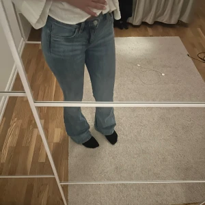 Blå bootcut jeans med normal passform - Säljer ett par klassiska blå jeans med bootcut-modell och normal passform. Jeansen har fem fickor, dragkedja och knapp framtill. Perfekta för dig som gillar en tidlös look med lite utsvängda ben. Materialet är mjukt och följsamt jeans.
