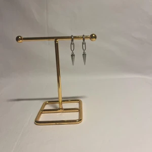 Silvriga örhängen med konformad detalj - Snygga silvriga örhängen med cool konformad hängande detalj. De har en modern och edgy vibe med små ringar och avlånga länkar. Perfekta för dig som gillar minimalistiska men ändå unika smycken.