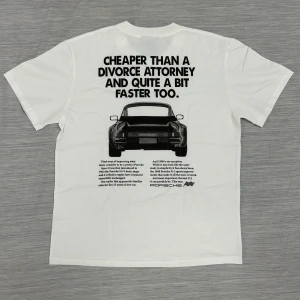 Vit Porsche t-shirt från Icevalley - Vit t-shirt från Icevalley med stor svart Porsche 911-print och text på ryggen. Klassisk passform med rund hals och korta ärmar. Tillverkad i mjuk bomull, perfekt för dig som gillar bilar och vill sticka ut med en unik grafisk design.