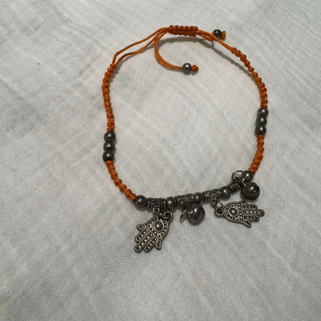 Orange ankellänk med hamsa-berlocker