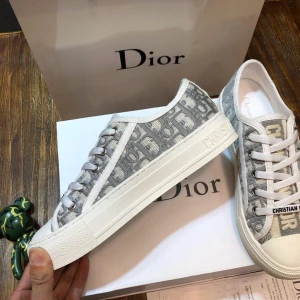 Dior Oblique (walk’n dior) i grått och vitt - Snygga Dior Oblique sneakers i grått och vitt med klassiskt monogrammönster. Skorna har rund tå, platt sula och vita snören med 'Christian Dior' tryckt på. Tillverkade i canvas med detaljer i skinn och gummisula. Perfekta för dig som vill ha en lyxig och trendig look.Allt og finns kvar