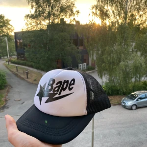 Bape Keps - Fet Bape keps i toppen skick. Justerbar storlek. Modellen är i trucker stil med glans tryck på framsidan. Har ni frågor så är det bara o ställa 